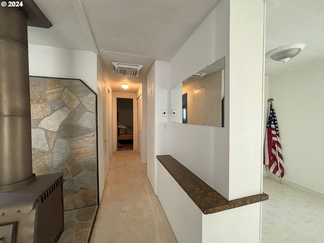 hall featuring a textured ceiling and light colored carpet