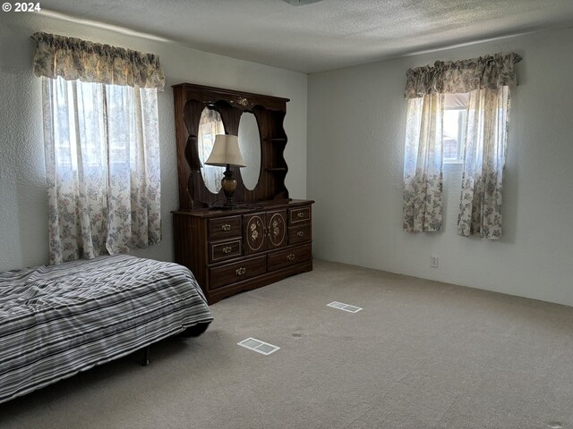 bedroom with light carpet and a textured ceiling