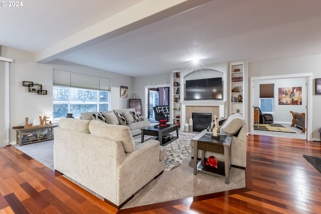 living room featuring built in features, hardwood / wood-style flooring, and beam ceiling