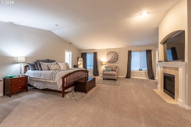 carpeted bedroom with a fireplace and vaulted ceiling