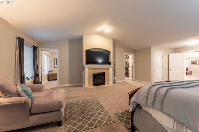 carpeted bedroom with a tiled fireplace and vaulted ceiling