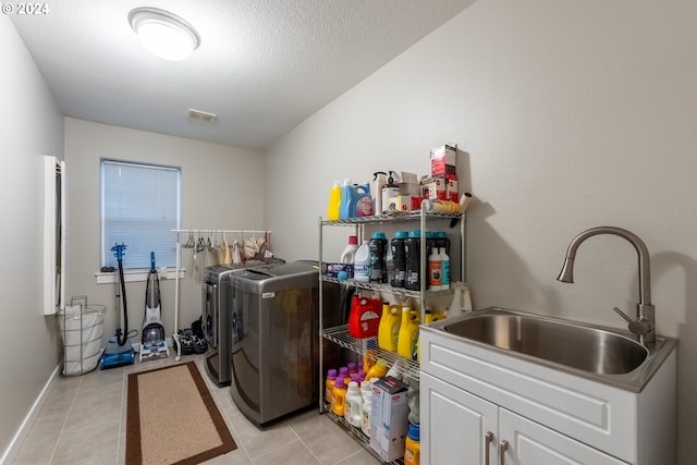 washroom with cabinets, sink, a textured ceiling, light tile patterned floors, and washing machine and dryer