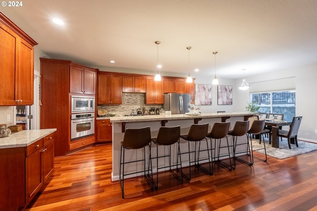 kitchen with pendant lighting, dark hardwood / wood-style flooring, a spacious island, and appliances with stainless steel finishes