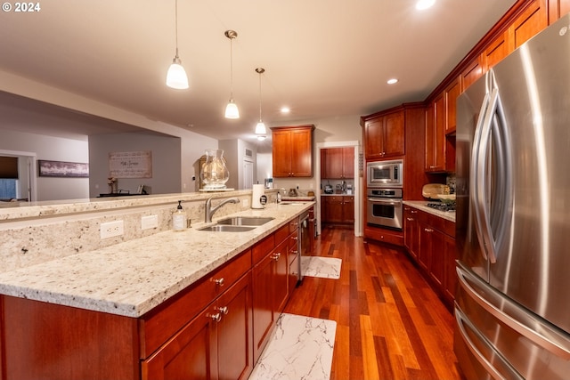 kitchen with sink, appliances with stainless steel finishes, pendant lighting, dark hardwood / wood-style floors, and a large island