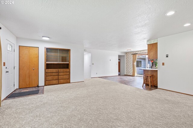 unfurnished living room featuring a textured ceiling and carpet flooring