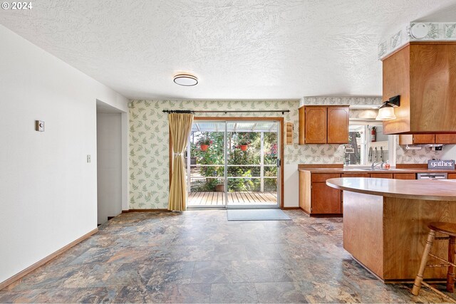 kitchen with a textured ceiling, kitchen peninsula, a breakfast bar area, and sink