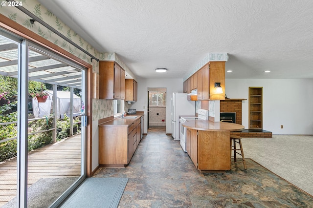 kitchen featuring dark carpet, white electric range oven, a brick fireplace, a textured ceiling, and a kitchen breakfast bar