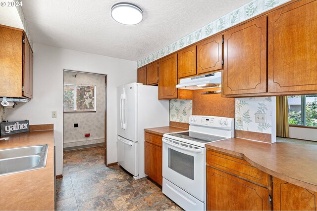 kitchen with white appliances, a textured ceiling, and sink