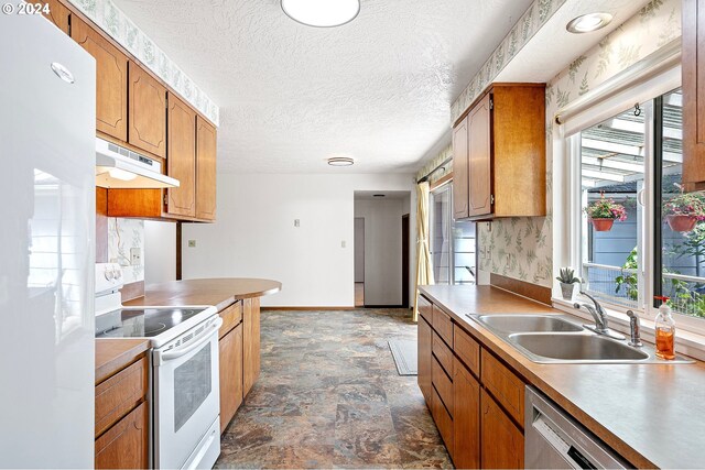 kitchen featuring white appliances, a textured ceiling, and sink