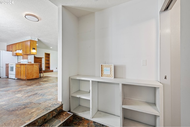 interior space featuring ventilation hood, a textured ceiling, and white appliances