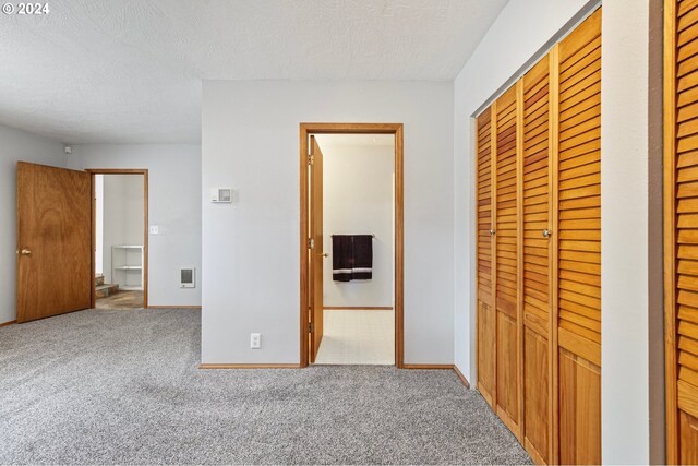 unfurnished bedroom featuring a textured ceiling, a closet, and carpet