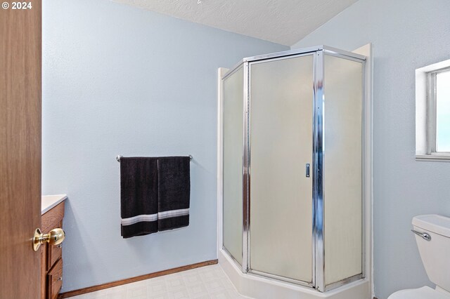 bathroom with a textured ceiling, vanity, toilet, and an enclosed shower