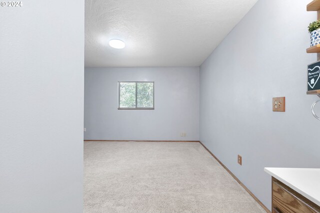 carpeted empty room featuring a textured ceiling