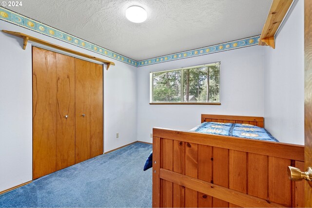 bedroom with a textured ceiling, carpet flooring, and a closet