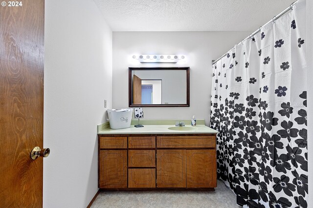 bathroom with a textured ceiling, walk in shower, and vanity