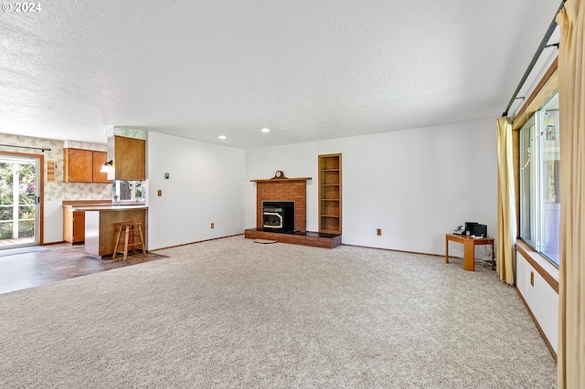 unfurnished living room featuring a textured ceiling, a fireplace, and dark colored carpet