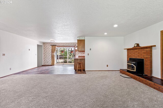 unfurnished living room featuring a brick fireplace, carpet, and a textured ceiling