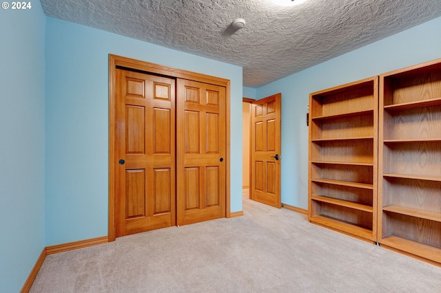 unfurnished bedroom featuring a textured ceiling and light colored carpet