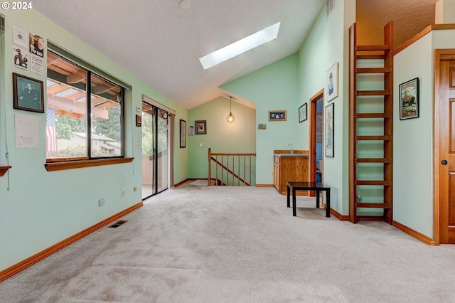 carpeted empty room with lofted ceiling with skylight