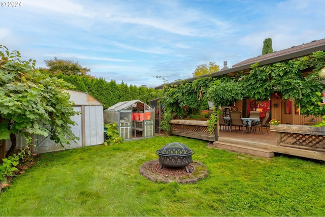 view of yard featuring a wooden deck, an outdoor fire pit, and a storage unit