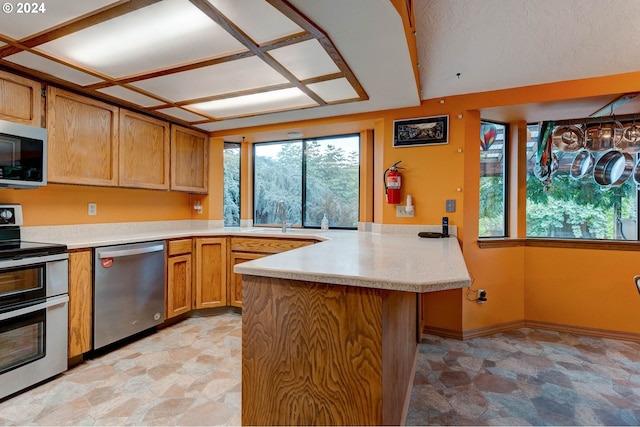 kitchen with plenty of natural light, stainless steel appliances, kitchen peninsula, and sink