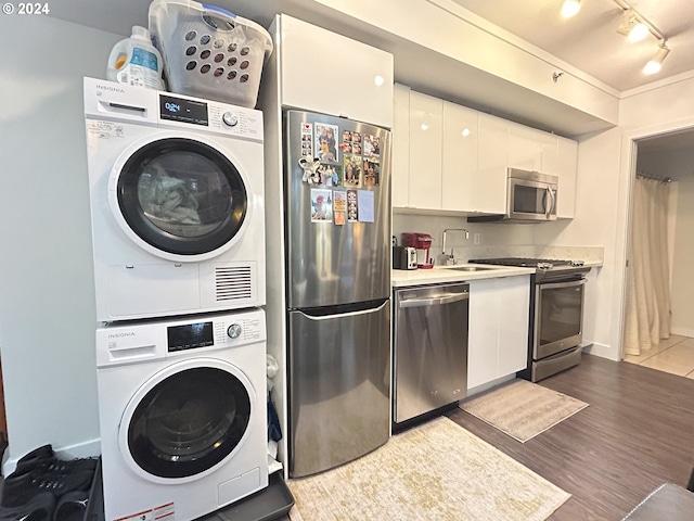 clothes washing area featuring sink, light wood-type flooring, and stacked washer and dryer