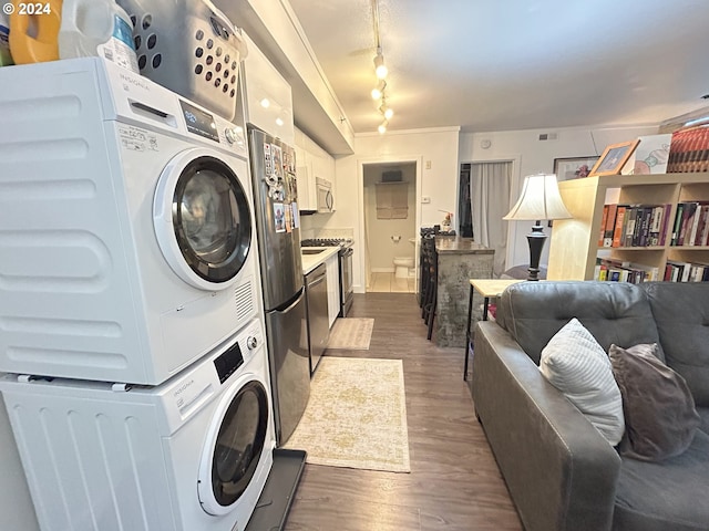 washroom featuring track lighting, stacked washing maching and dryer, ornamental molding, and dark wood-type flooring