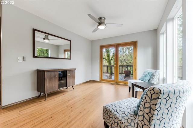 sitting room with ceiling fan, french doors, and light wood-type flooring