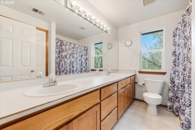 bathroom featuring vanity, a healthy amount of sunlight, and toilet