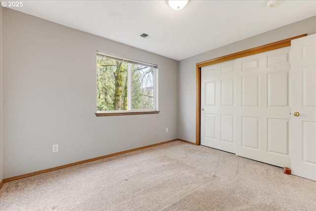 unfurnished bedroom with a closet and light colored carpet