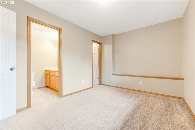 unfurnished bedroom featuring ensuite bath and light carpet