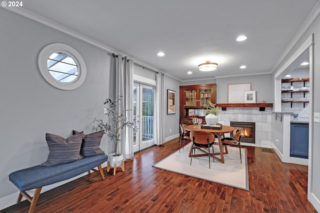 dining room featuring french doors, dark hardwood / wood-style flooring, ornamental molding, and a tiled fireplace