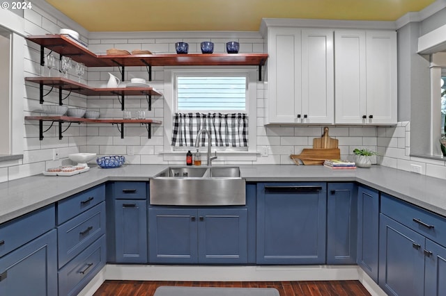 kitchen with white cabinets, decorative backsplash, blue cabinetry, and sink