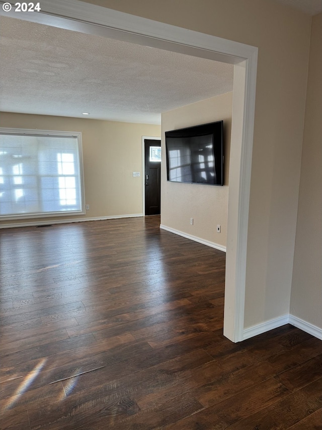 unfurnished room featuring dark hardwood / wood-style flooring and a textured ceiling