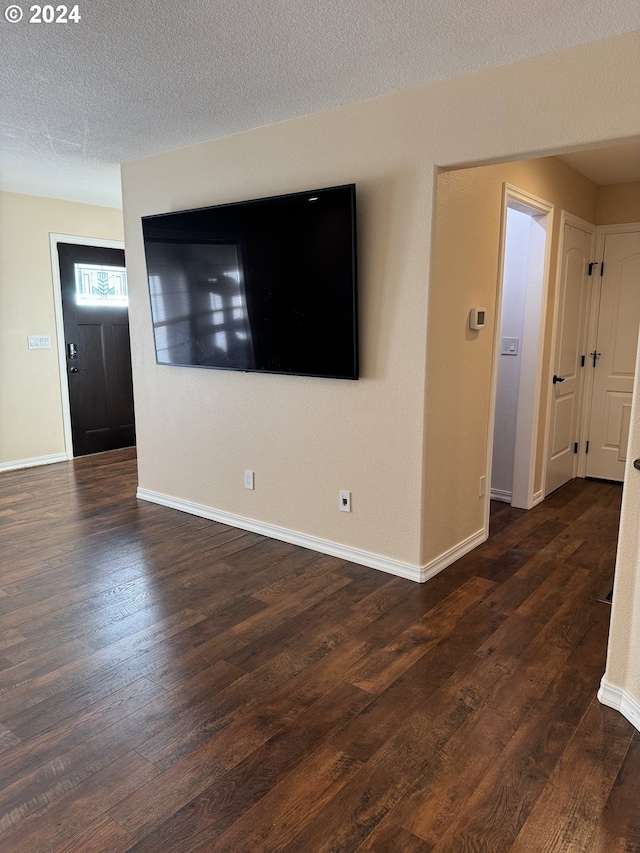 unfurnished living room featuring a textured ceiling and dark hardwood / wood-style floors