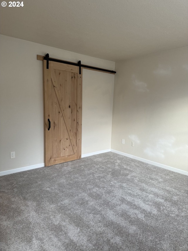 unfurnished room featuring a barn door, carpet, and a textured ceiling