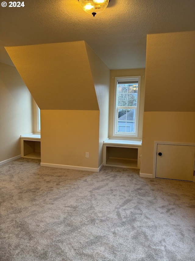 bonus room featuring carpet, lofted ceiling, and a textured ceiling