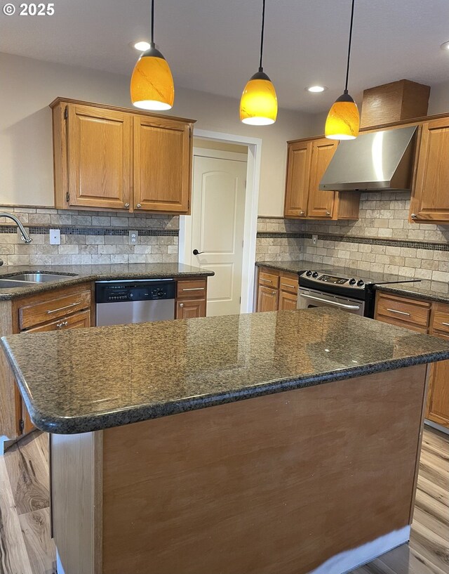 kitchen with dark hardwood / wood-style floors, hanging light fixtures, stainless steel appliances, and wall chimney range hood