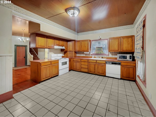 kitchen with decorative light fixtures, sink, white appliances, kitchen peninsula, and an inviting chandelier