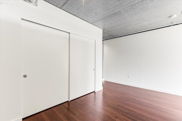 unfurnished bedroom with dark hardwood / wood-style flooring and a closet