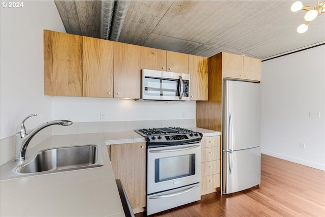 kitchen with sink, light wood-type flooring, stainless steel appliances, and light brown cabinetry