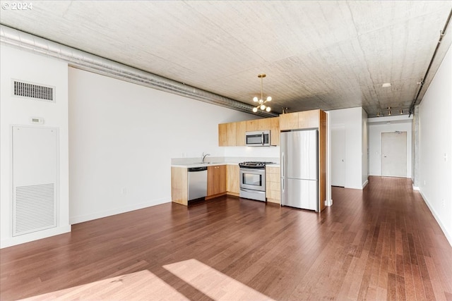 kitchen with appliances with stainless steel finishes, dark hardwood / wood-style flooring, sink, pendant lighting, and a chandelier