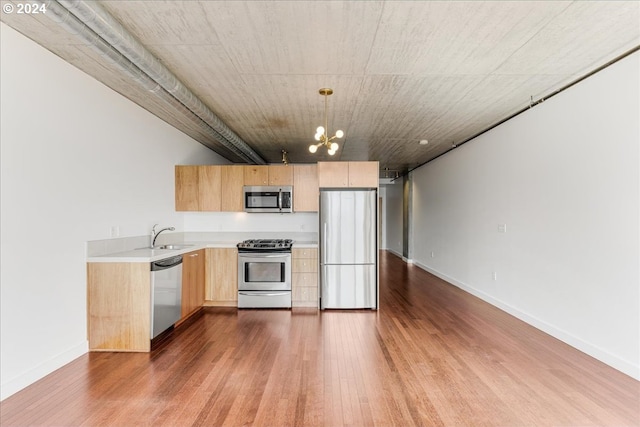 kitchen with appliances with stainless steel finishes, light brown cabinetry, decorative light fixtures, a chandelier, and dark hardwood / wood-style floors