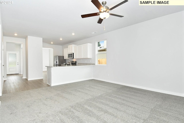 kitchen with stainless steel appliances, white cabinets, carpet flooring, and ceiling fan