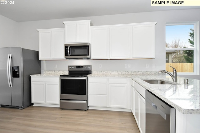 kitchen with white cabinets, appliances with stainless steel finishes, sink, and light hardwood / wood-style floors