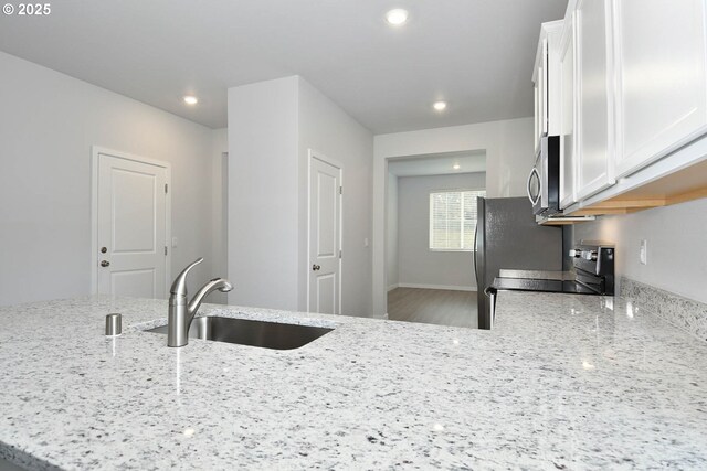 kitchen with kitchen peninsula, white cabinets, light wood-type flooring, and stainless steel appliances