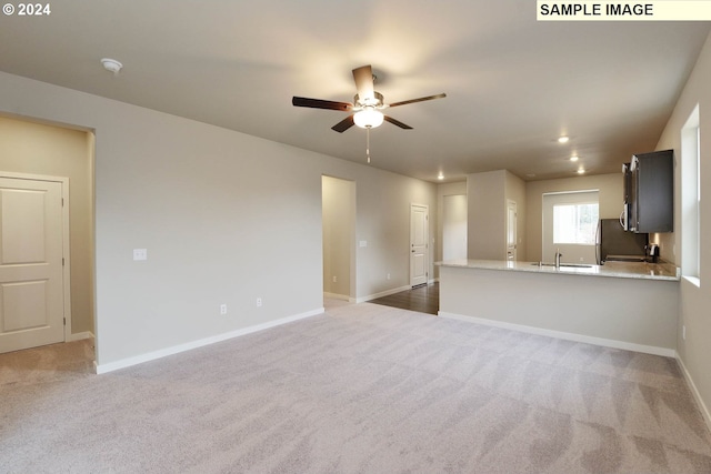 unfurnished living room with sink, carpet, and ceiling fan