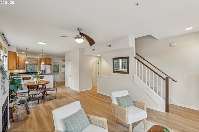 living room featuring sink, ceiling fan, and light hardwood / wood-style flooring