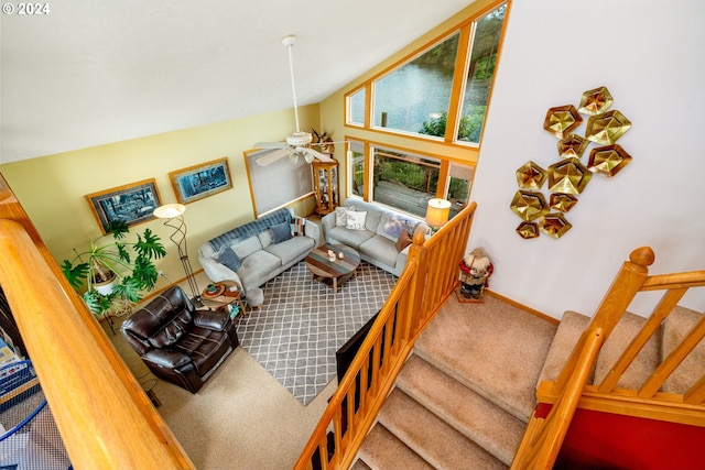 carpeted living room with ceiling fan and high vaulted ceiling