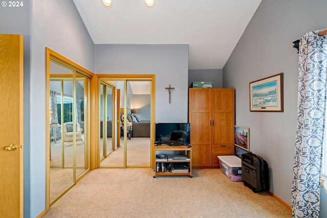 interior space featuring vaulted ceiling, light carpet, and two closets